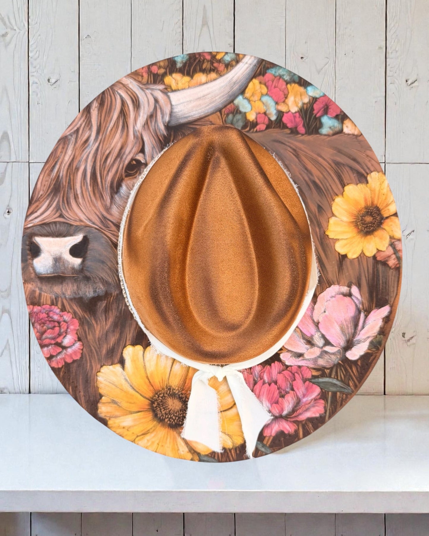 Wide brim hat with a highland cow, and floral design on a wooden background