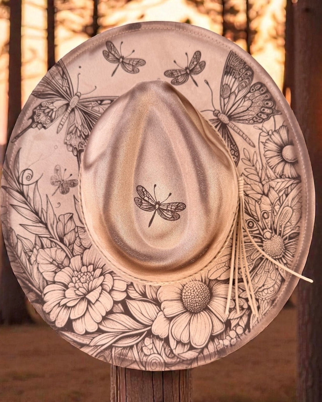 Decorative hat with butterfly and floral patterns against a blurred natural background