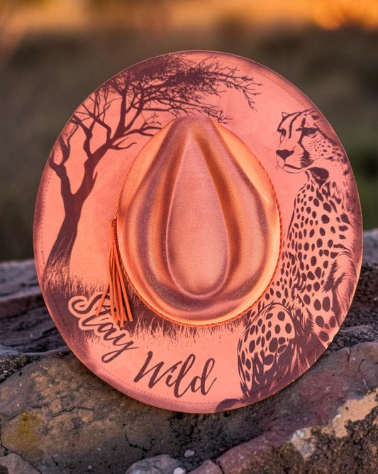 Wide brim hat with nature-themed cheetah design on a rock at sunset