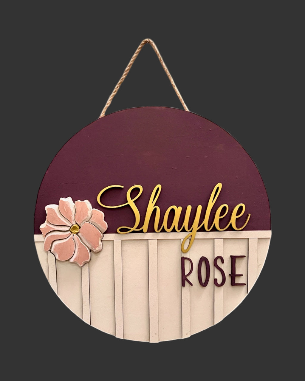 Round wooden sign with floral design and custom text on a grey background